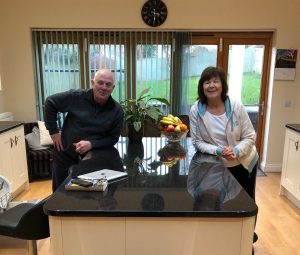 2020Lesley and Tony in kitchen e1583230899426 300x255 - Shared Lives South West Carer Lesley and Tony in their kitchen