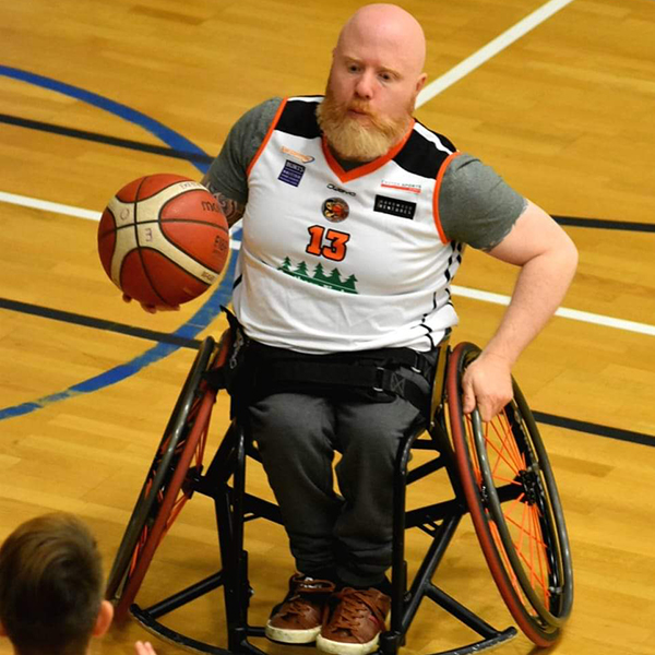Nick Jessup playing wheelchair basketball for Exeter Otters. He is pictured with the basketball moving wearing his basketball jersey.