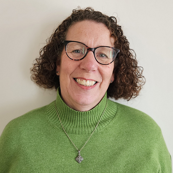 Shared Lives Coordinator Jo Polkey, wearing a great high neck jumper. She also has a celtic inspired necklace on and is wearing glasses.