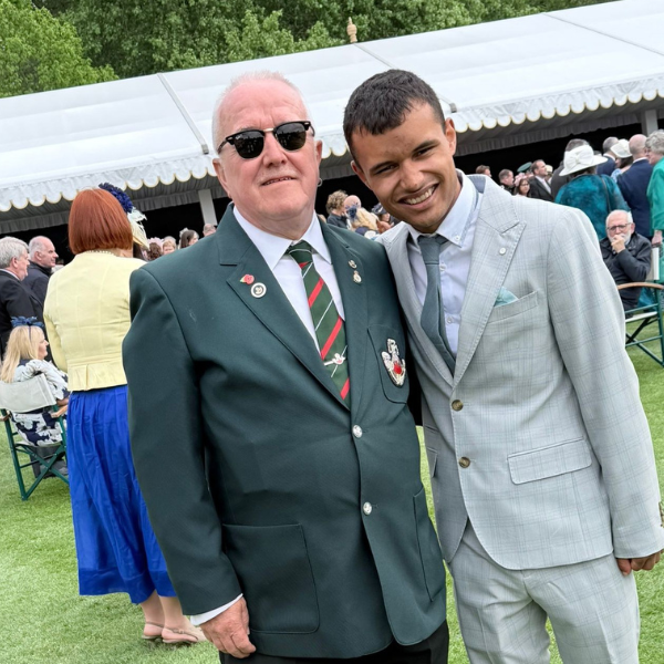 Paul Kendell and the person he supported dressed in suits at the Buckingham Palace garden party. They are pictured in front of the tent.