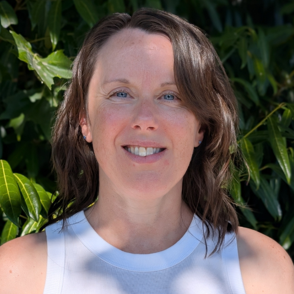 Lucy Foord is pictured outside with greenery behind her on a sunny day. She is wearing a white vest top.